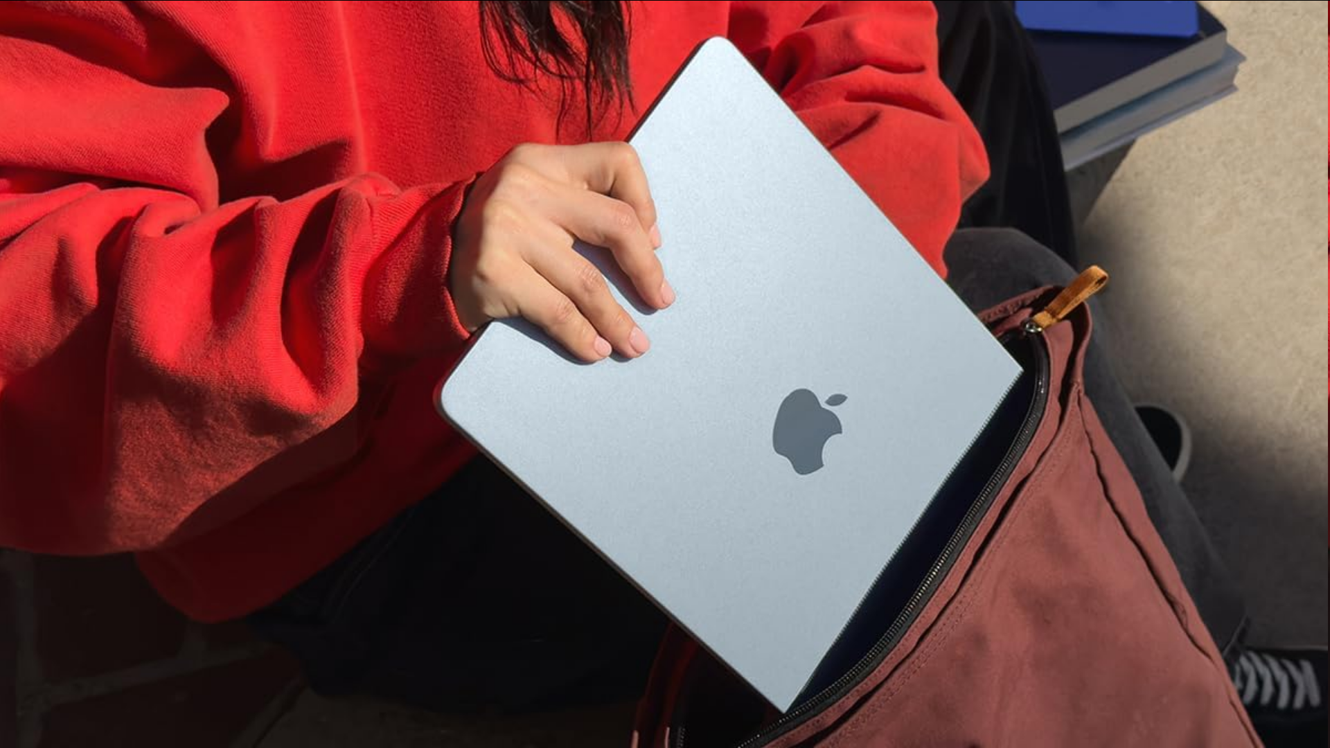 A person putting an Apple MacBook into a bag