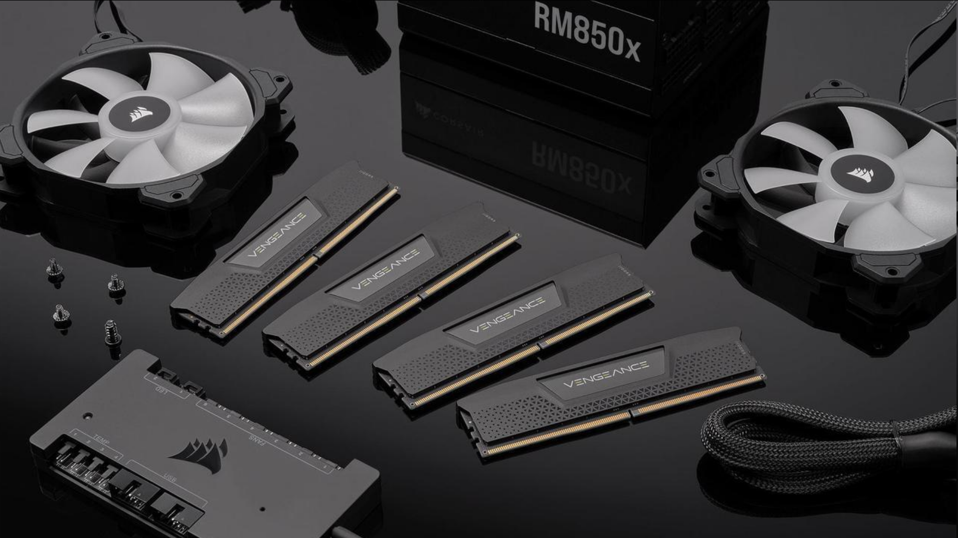 An image of Corsair Vengeance 64 GB memory kit, spread on a black shiny platform, surrounded by other corsair products